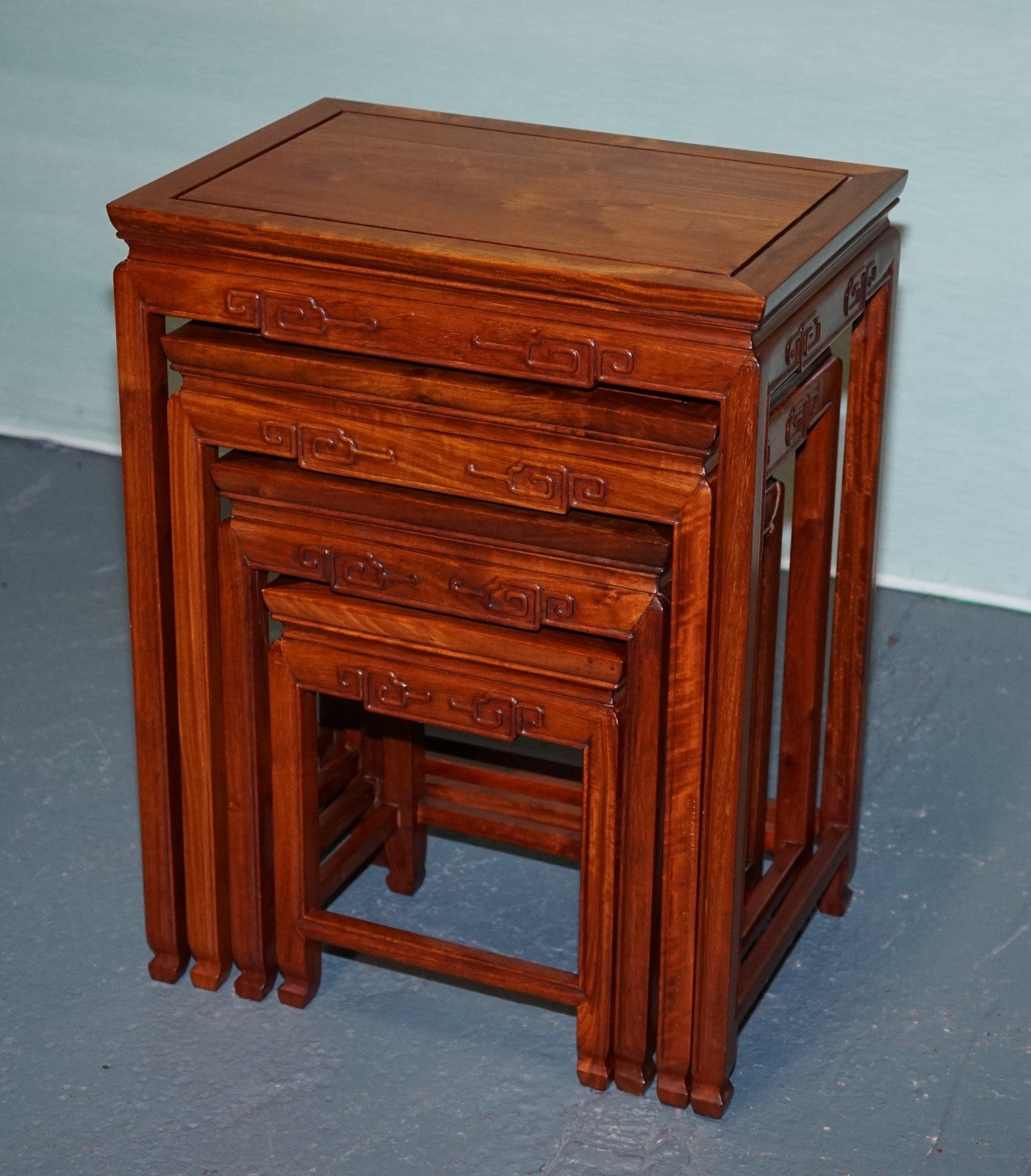 ORIENTAL CHINESE TEAK NEST OF FOUR TABLES WITH CARVED DETAILS