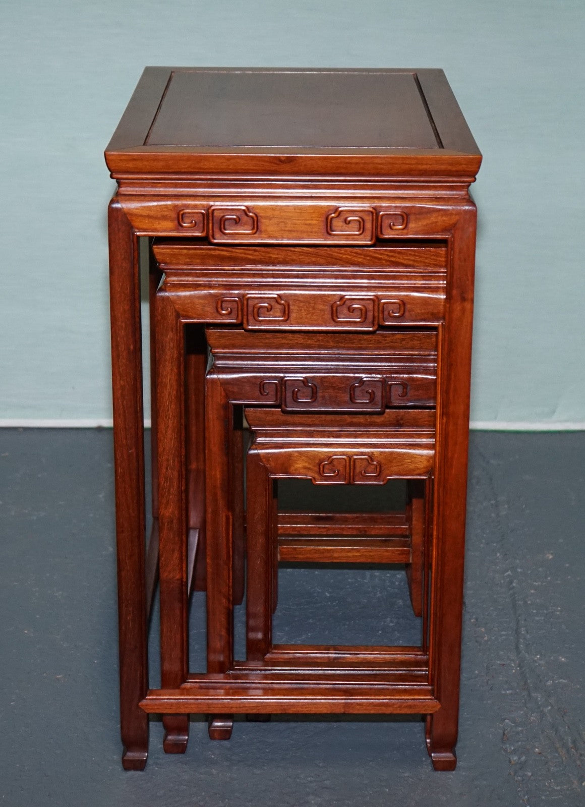 ORIENTAL CHINESE TEAK NEST OF FOUR TABLES WITH CARVED DETAILS